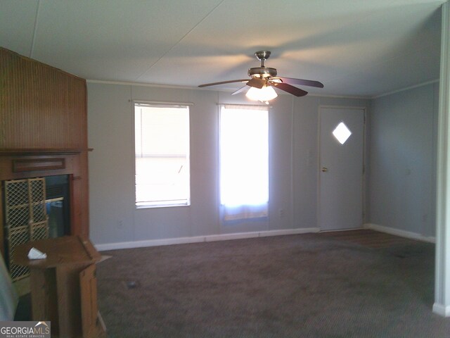 unfurnished living room featuring ornamental molding and dark carpet