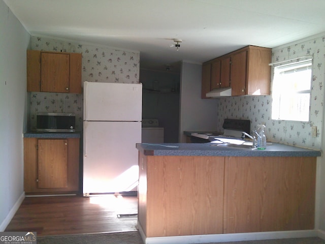 kitchen with dark wood-type flooring, washer / dryer, sink, white fridge, and stove