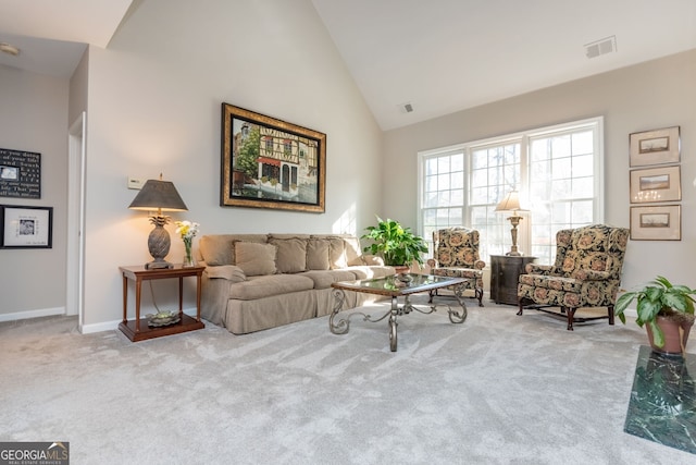 carpeted living room with high vaulted ceiling