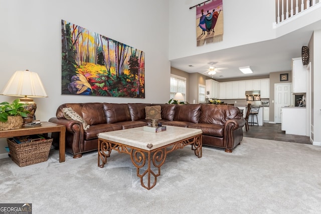 living room with light colored carpet, ceiling fan, and a high ceiling