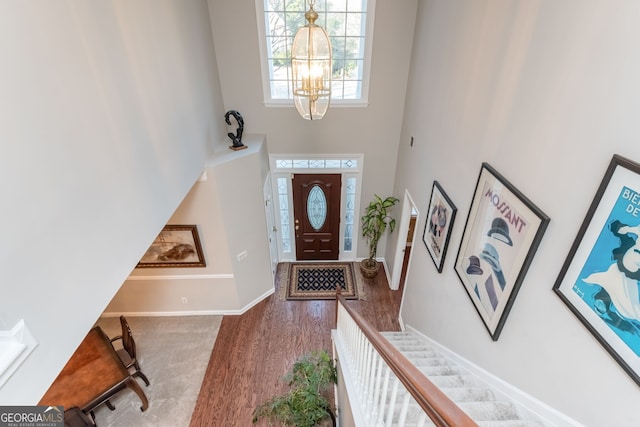 foyer entrance featuring a high ceiling, hardwood / wood-style floors, and an inviting chandelier