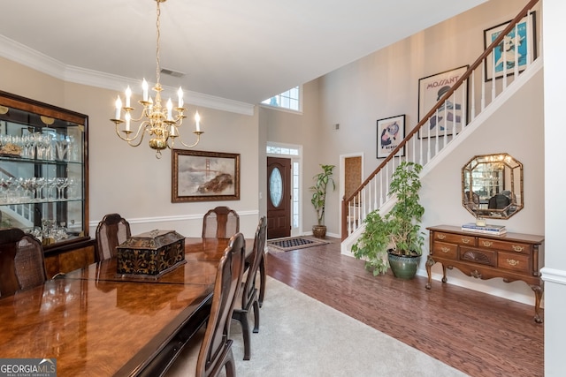 dining room with wood-type flooring, ornamental molding, and a chandelier