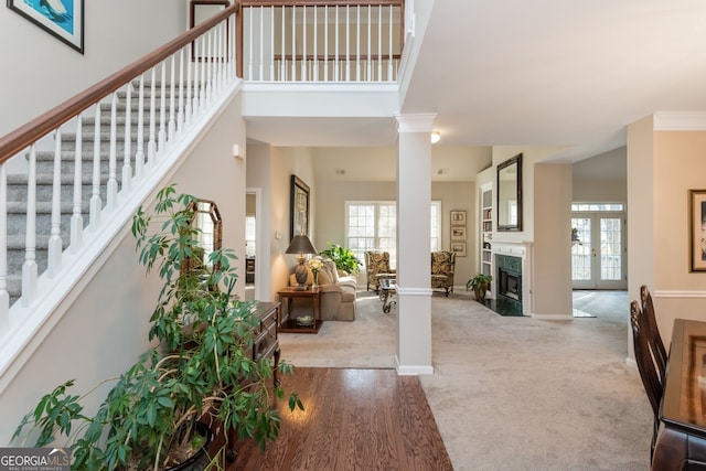 foyer featuring ornate columns, a premium fireplace, a towering ceiling, and light colored carpet