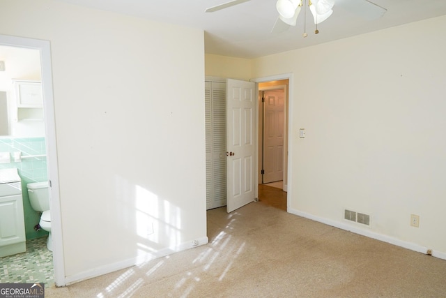 unfurnished bedroom with ensuite bathroom, light colored carpet, ceiling fan, and a closet