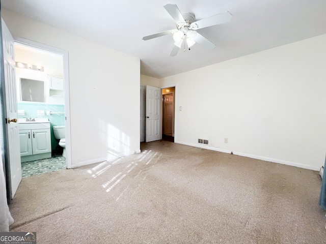 unfurnished bedroom with ceiling fan, carpet, connected bathroom, and sink