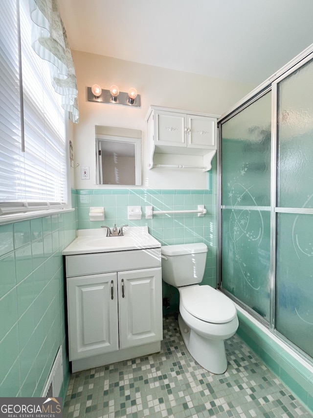 bathroom featuring a shower with door, vanity, tile walls, and tile patterned floors