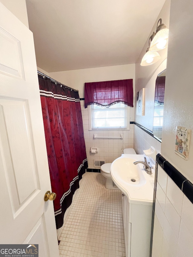 bathroom with toilet, tile walls, and vanity