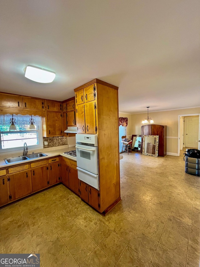 kitchen featuring tasteful backsplash, sink, an inviting chandelier, white appliances, and hanging light fixtures