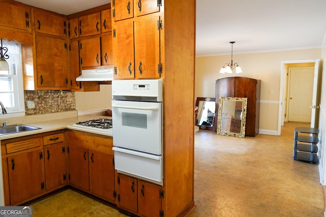 kitchen with backsplash, a notable chandelier, white appliances, pendant lighting, and sink