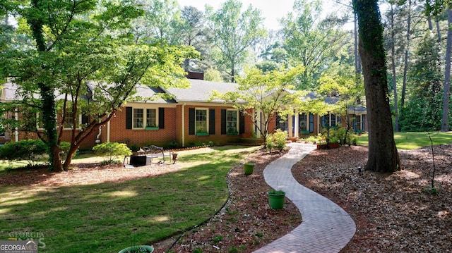 single story home with a chimney, a front lawn, and brick siding