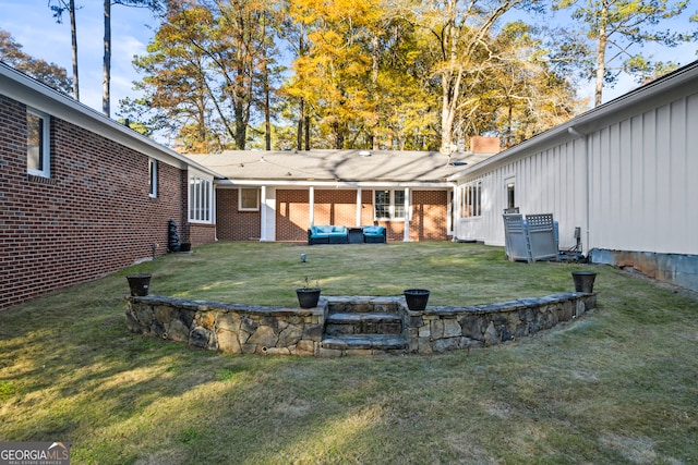 back of house featuring brick siding and a lawn