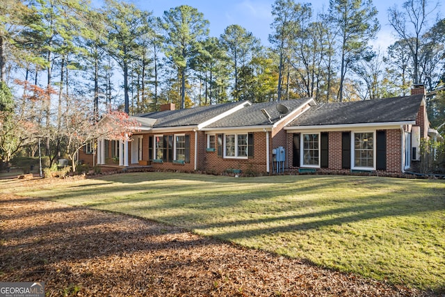 single story home featuring a chimney, a front lawn, and brick siding