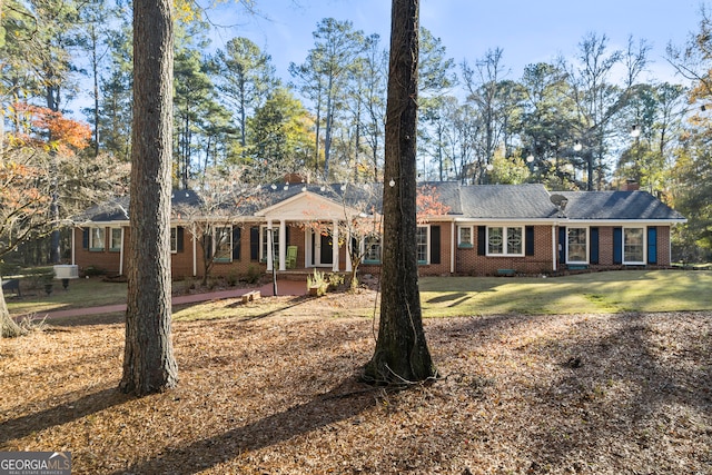 single story home with brick siding, a front lawn, and a chimney