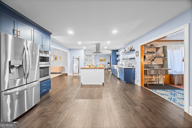 kitchen with island exhaust hood, blue cabinetry, stainless steel appliances, light countertops, and dark wood-type flooring