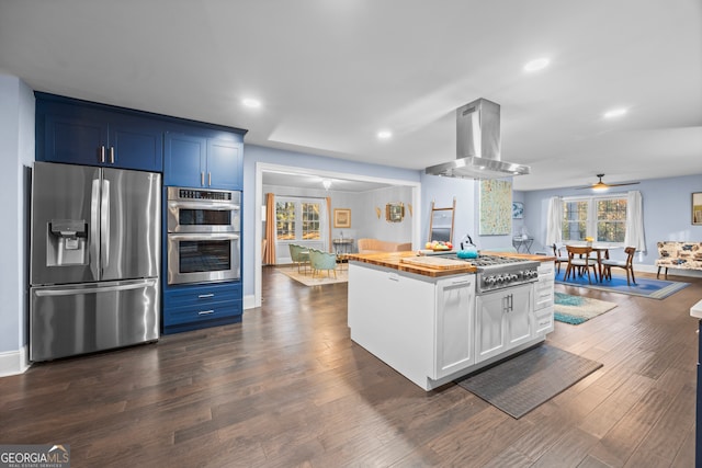 kitchen with appliances with stainless steel finishes, white cabinetry, island exhaust hood, and blue cabinetry