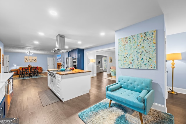 kitchen with island range hood, white cabinets, a kitchen island, wood counters, and dark wood-type flooring