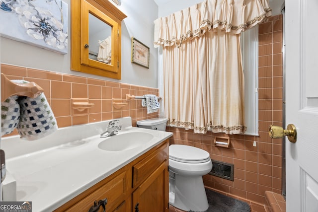 full bath featuring toilet, a wainscoted wall, vanity, visible vents, and tile walls