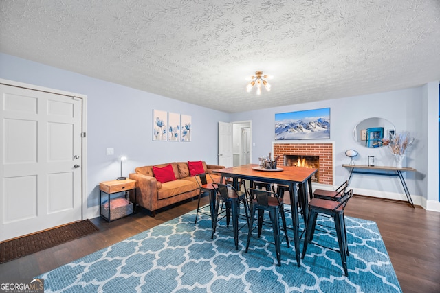 dining room featuring dark wood-style floors, a fireplace, a textured ceiling, and baseboards