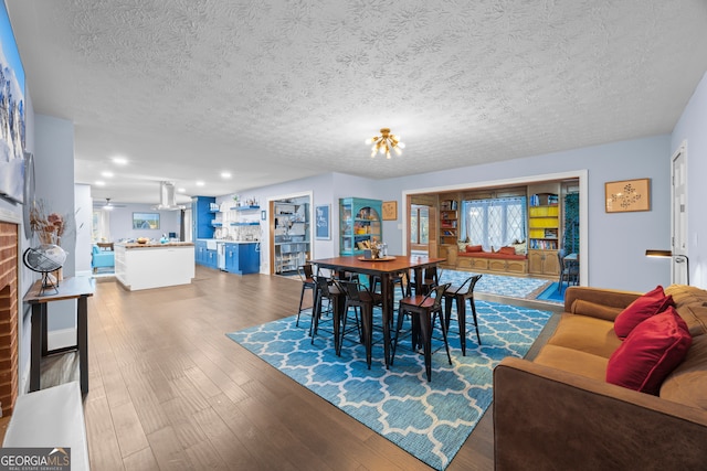 dining space with a brick fireplace, a textured ceiling, and wood finished floors