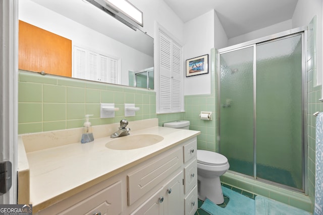 bathroom featuring toilet, tile patterned flooring, vanity, a shower stall, and tile walls