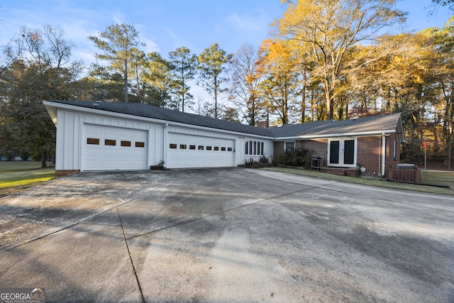 view of front facade featuring french doors, brick siding, an attached garage, board and batten siding, and driveway