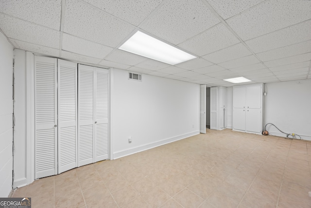 finished below grade area with baseboards, visible vents, and a drop ceiling