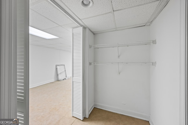 walk in closet with a paneled ceiling and light tile patterned flooring