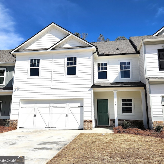 view of front of property featuring an attached garage, a shingled roof, and concrete driveway