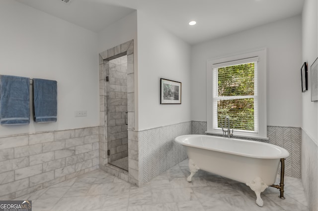 bathroom featuring tile walls and separate shower and tub