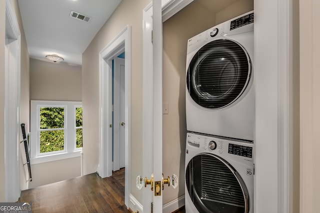 laundry room with stacked washer and dryer and dark wood-type flooring