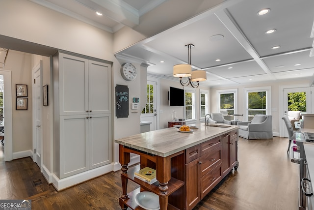 kitchen featuring dark hardwood / wood-style floors, pendant lighting, sink, coffered ceiling, and an island with sink