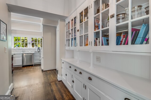 interior space with decorative backsplash, dishwasher, sink, and hardwood / wood-style flooring