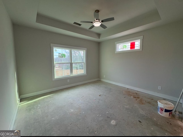 spare room with ceiling fan and a tray ceiling