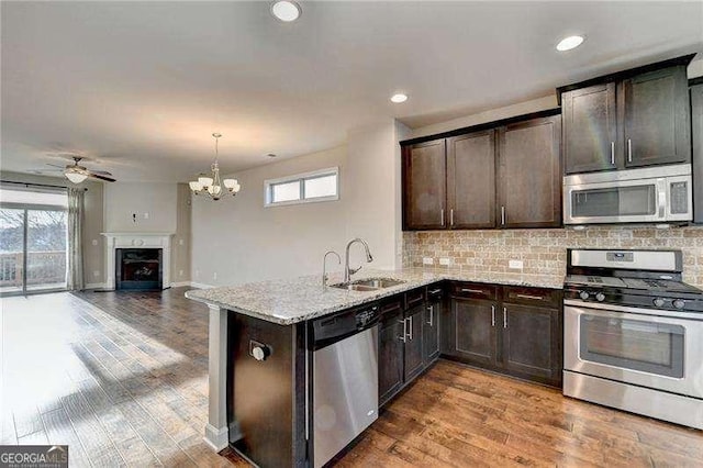 kitchen featuring pendant lighting, stainless steel appliances, sink, backsplash, and kitchen peninsula