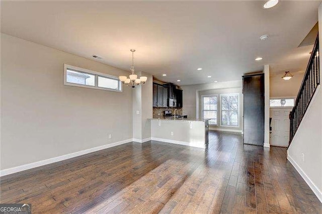 unfurnished living room featuring dark hardwood / wood-style floors and an inviting chandelier