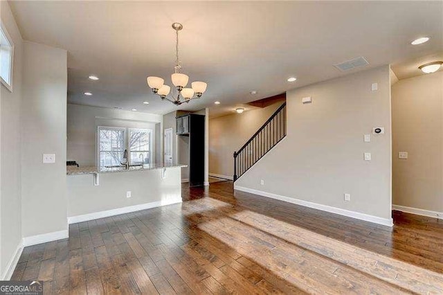 unfurnished living room featuring dark hardwood / wood-style flooring and a notable chandelier