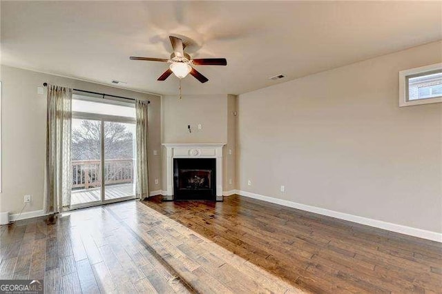 unfurnished living room with ceiling fan, a wealth of natural light, and dark hardwood / wood-style flooring