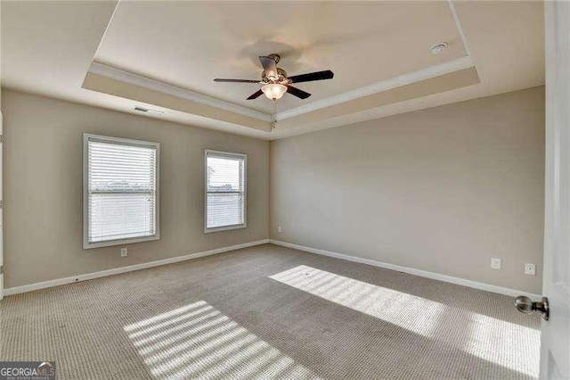 unfurnished room featuring ceiling fan, light carpet, and a tray ceiling