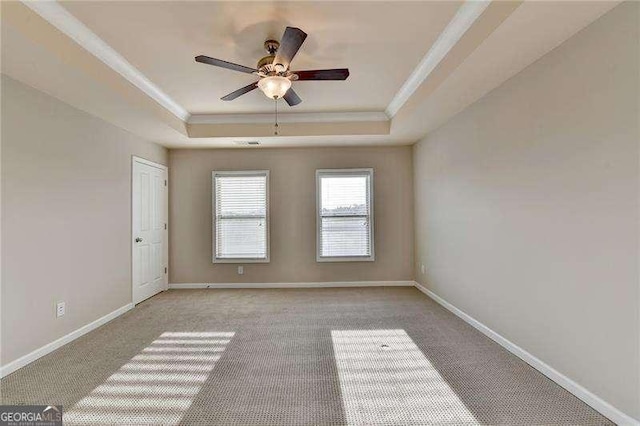 carpeted spare room featuring ceiling fan, a tray ceiling, and ornamental molding