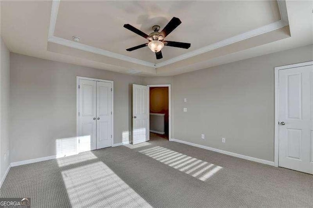 carpeted bedroom with ceiling fan and a raised ceiling