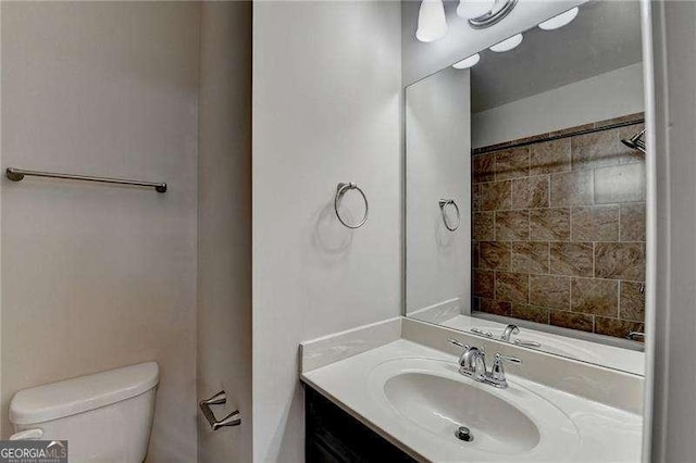 bathroom featuring toilet, vanity, and a tile shower