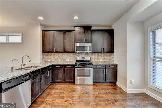 kitchen with plenty of natural light, appliances with stainless steel finishes, backsplash, and light stone counters