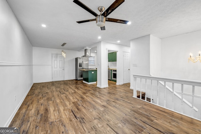 unfurnished living room featuring ceiling fan, hardwood / wood-style floors, and a textured ceiling