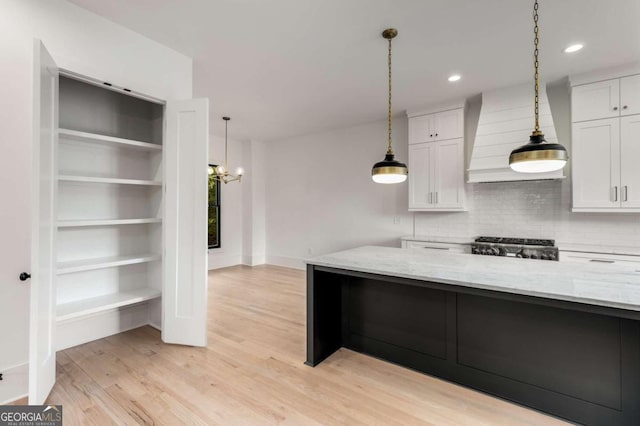 kitchen with white cabinets, light wood-type flooring, light stone countertops, and custom range hood