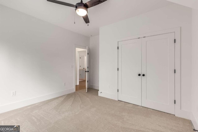 unfurnished bedroom with ceiling fan, a closet, and light colored carpet