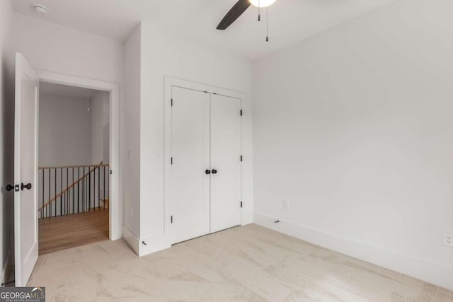 unfurnished bedroom featuring ceiling fan, a closet, and light colored carpet