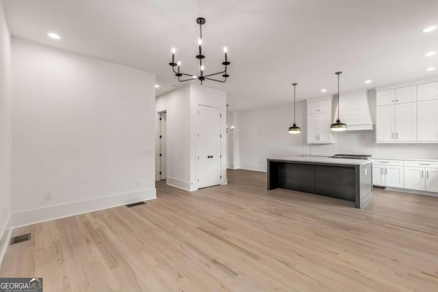 kitchen featuring decorative light fixtures, a center island, custom exhaust hood, light hardwood / wood-style flooring, and white cabinets