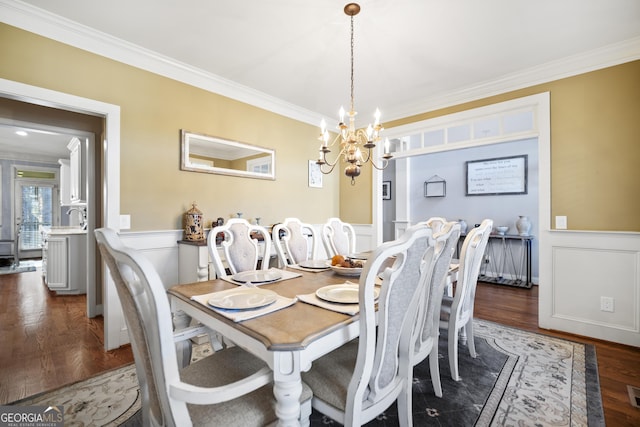 dining area featuring ornamental molding, dark wood-type flooring, and a chandelier