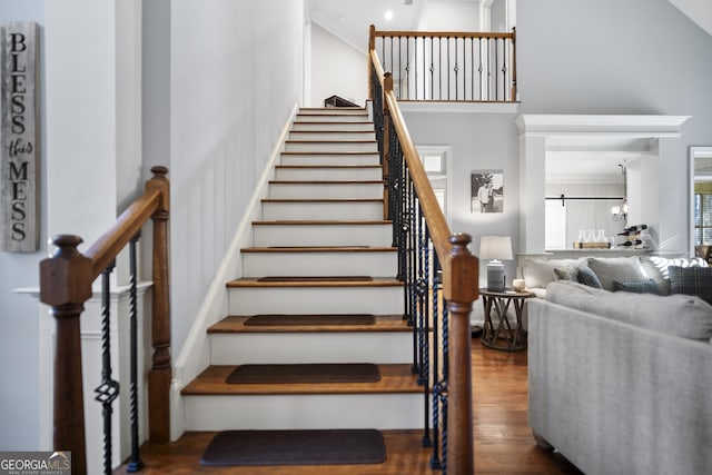 stairs with ornamental molding and hardwood / wood-style floors