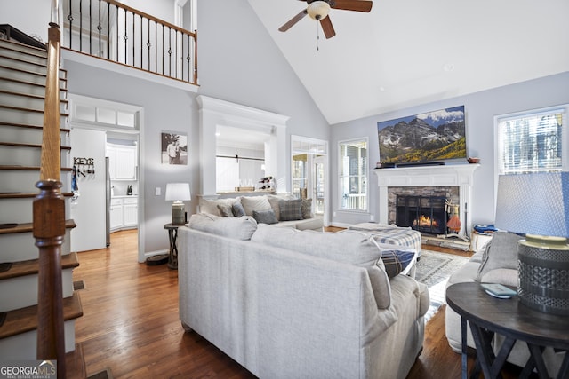 living room with hardwood / wood-style flooring, ceiling fan, a fireplace, and high vaulted ceiling